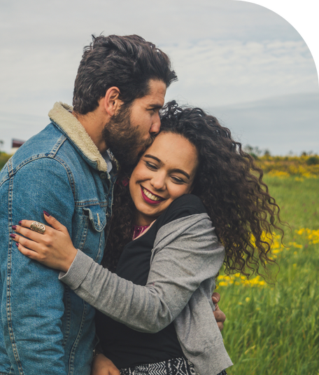 Image of a BIPOC couple hugging in a meadow.